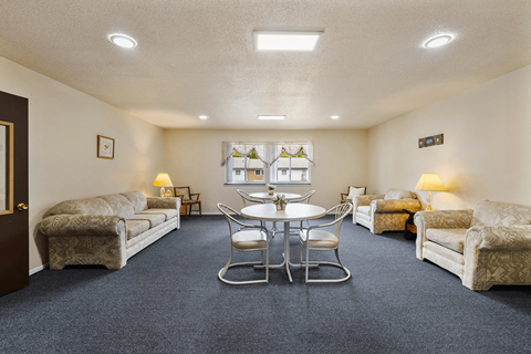 A living room with a round table and chairs in the center.