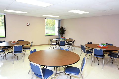 Community room with tables and chairs at Kentwood Square Apartments.