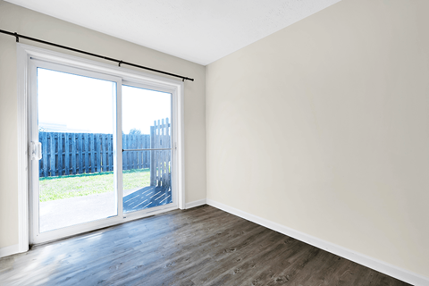 an empty living room with a sliding glass door and wood flooring