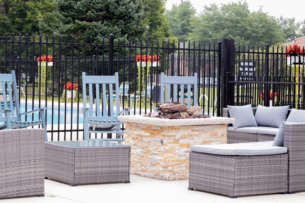 a seating area with chairs and a fire pit in front of a fence