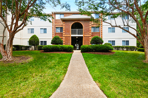 A building with a brick arched entrance and a concrete walkway leading to it.