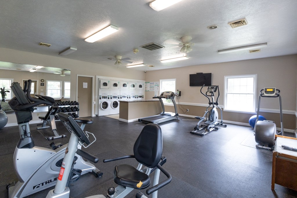 a gym with treadmills and other exercise equipment and a tv