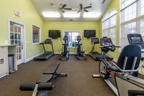 A gym with treadmills, elliptical machines, and a fan.