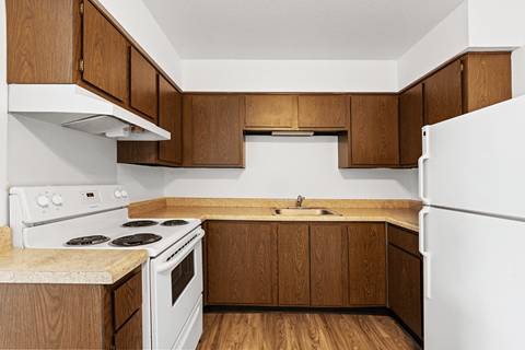 A kitchen with white appliances and wooden cabinets.