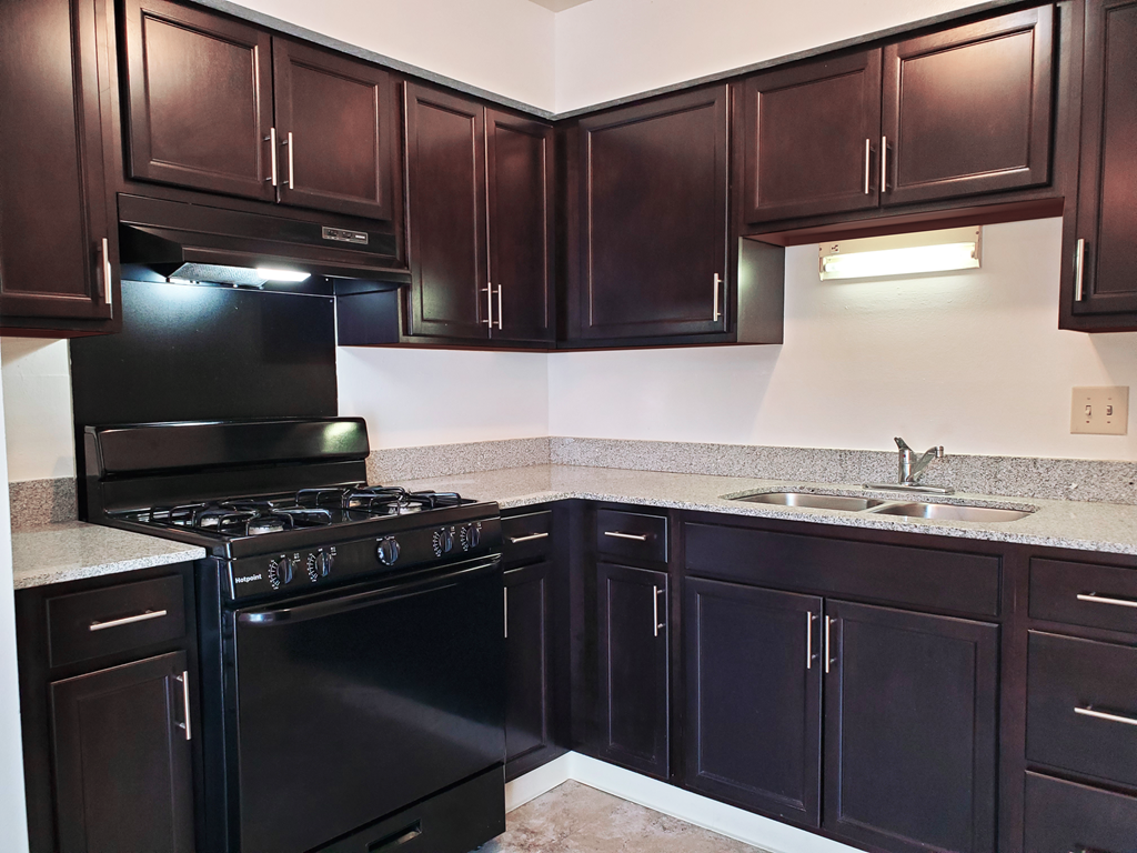 Kitchen in a 1 bedroom apartment with black appliances and dark wood cabinets at Carriage House West.