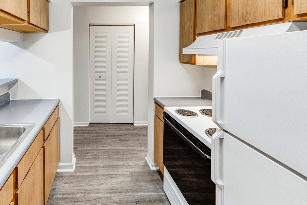 Kitchen in a 2-bedroom, 1-bath apartment at Woodland Crossing, featuring kitchen appliances, wood cabinetry, and counter space.