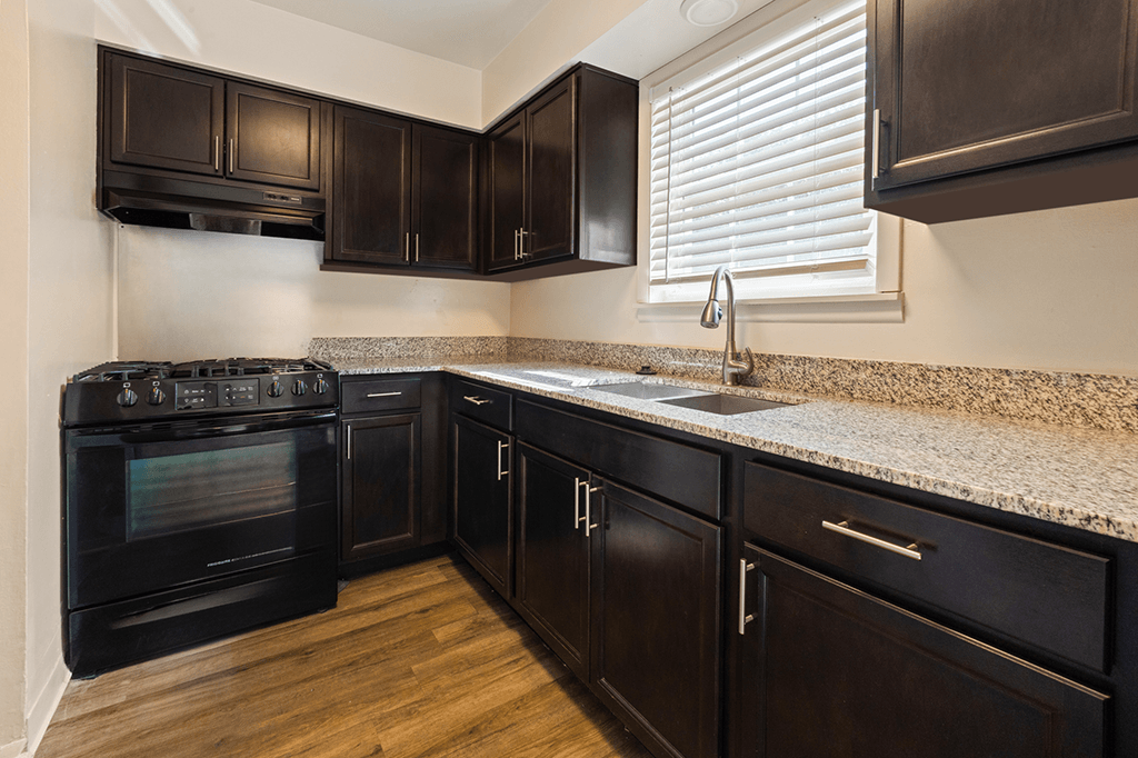 Kitchen with cabinets, stove and granite countertop in a 2-bed, 1.5-bath townhome at Carriage House Apartments in Kendallville.