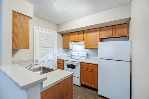 A kitchen with a white fridge, white sink, and white counter.