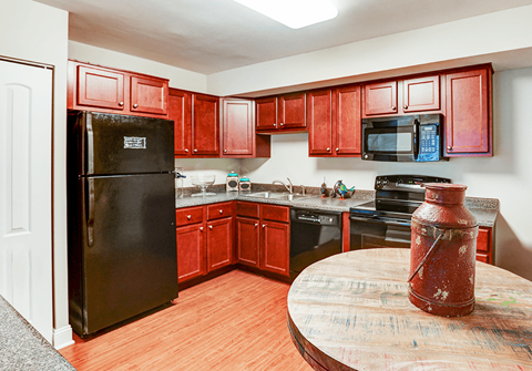 A kitchen with red cabinets and a black fridge.