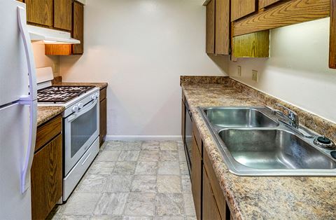 Kitchen with refrigerator, oven, sink, and plentiful cabinetry at Briarwood Apartments in Columbus, IN