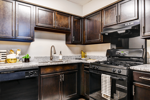 A kitchen with dark wood cabinets and a black stove top oven.