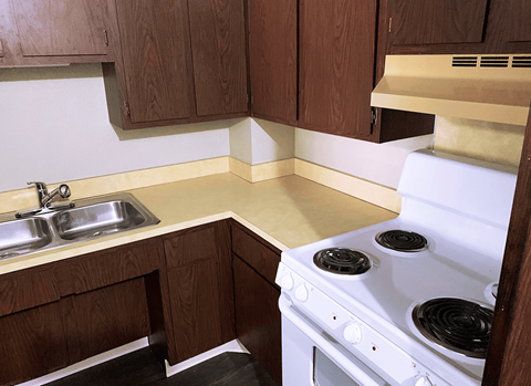 A white stove is in a kitchen with wooden cabinets.