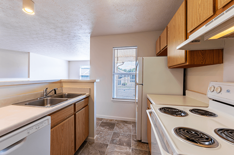 A kitchen with a white stove top oven and a white dishwasher.