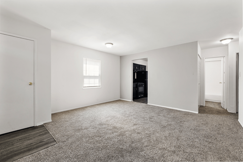 a bedroom with white walls and carpet and a door to a closet