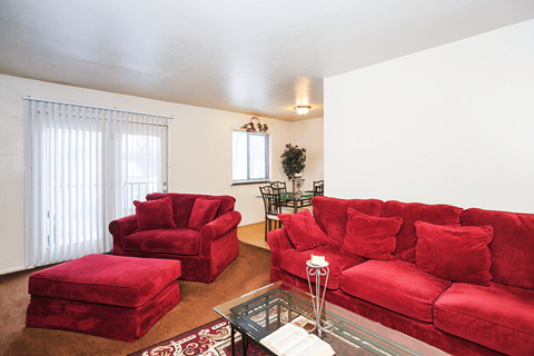 A living room with red furniture and a glass coffee table.