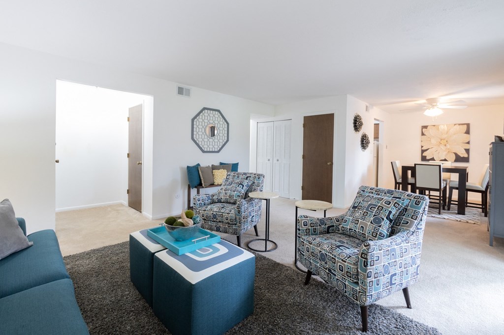 a living room with two blue chairs and a blue ottoman