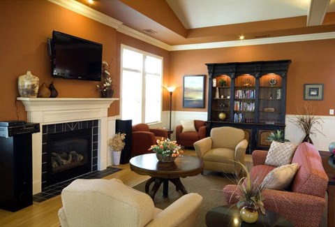 A living room with a fireplace, chairs, and a television.