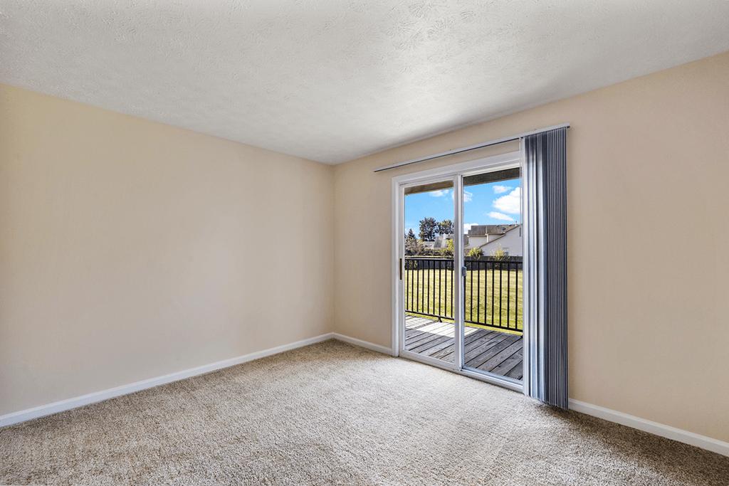 Master bedroom in a 3-bed, 2-bath apartment at Brownsburg Pointe with carpeted floors and a sliding glass door leading to a balcony.
