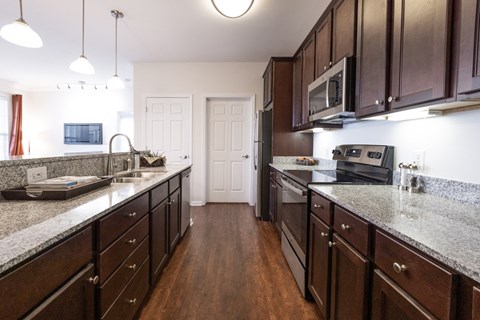 A kitchen with dark wood cabinets and granite countertops.