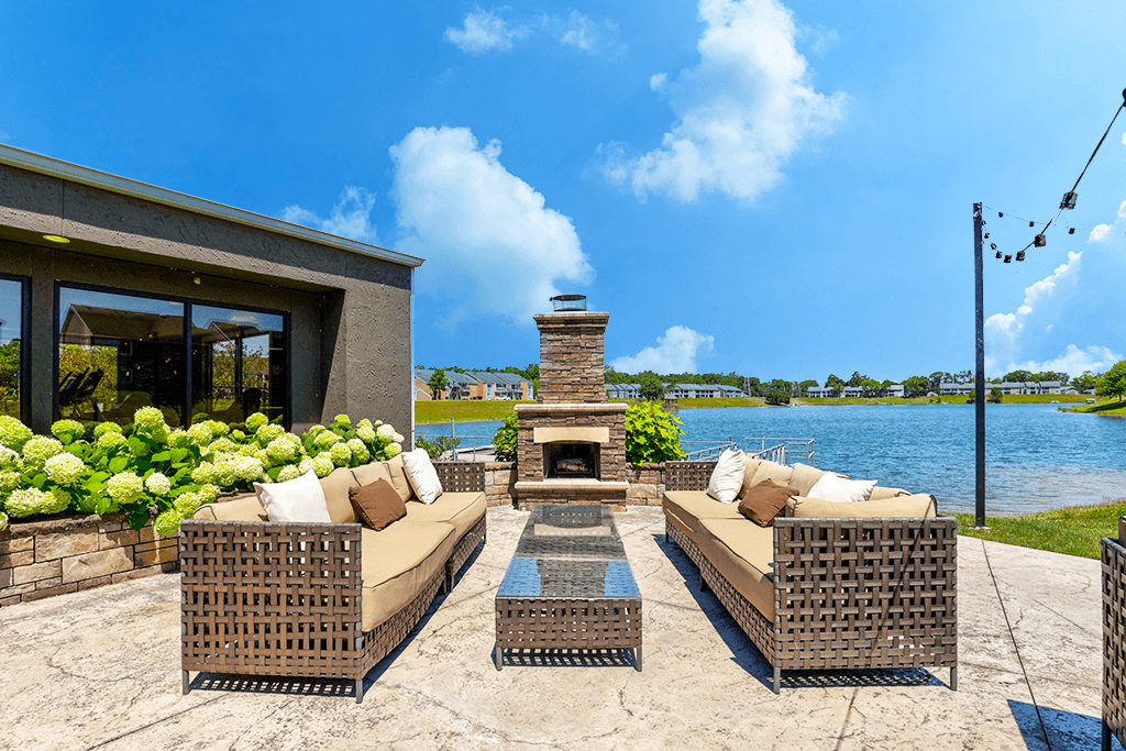 Outdoor entertainment area at Somerset Lakes Apartments, featuring a patio with a fireplace, seating, and views of the water