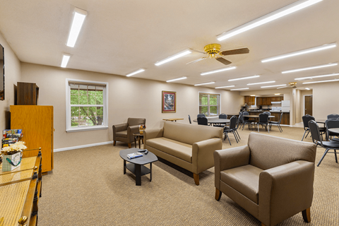 A spacious waiting room with a piano, chairs, and a ceiling fan.