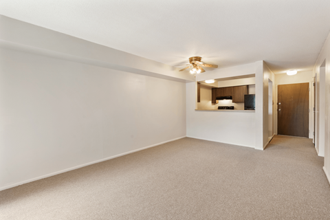 A spacious room with a ceiling fan and a small kitchenette.