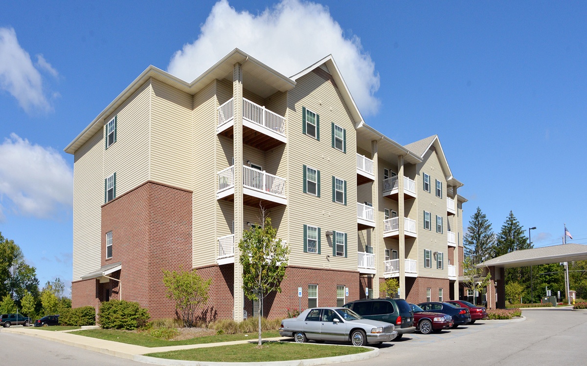 A large apartment building with a parking lot in front.