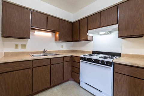 A kitchen with brown cabinets and a white stove top oven.