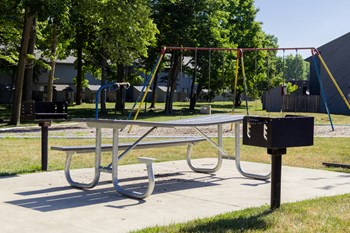 Picnic Table and Grilling Station Exterior Amenities at Woodlake Apartments Playground with a picnic table and a grilling station at Woodlake apartments