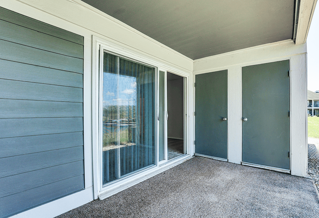 Patio with a sliding glass door at Somerset Lakes Apartments, offering a private outdoor space for relaxation. and a grey door.