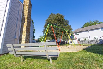 Playground with swing sets and bench seating at Woodbridge Apartments Bloomington - Photo Gallery 6