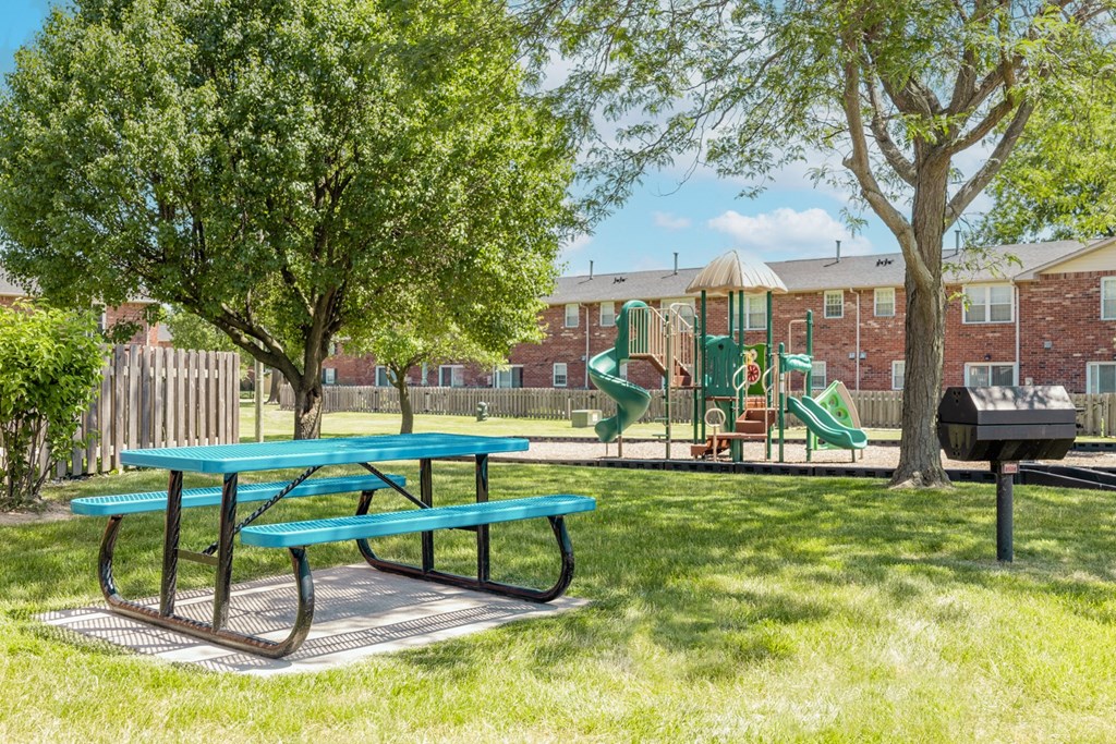 Picnic table in a park with a playground at Archer's Pointe.