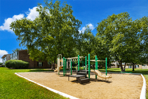 Playground at Briarwood Apartments, Columbus, IN, with swings, slides, and green space.