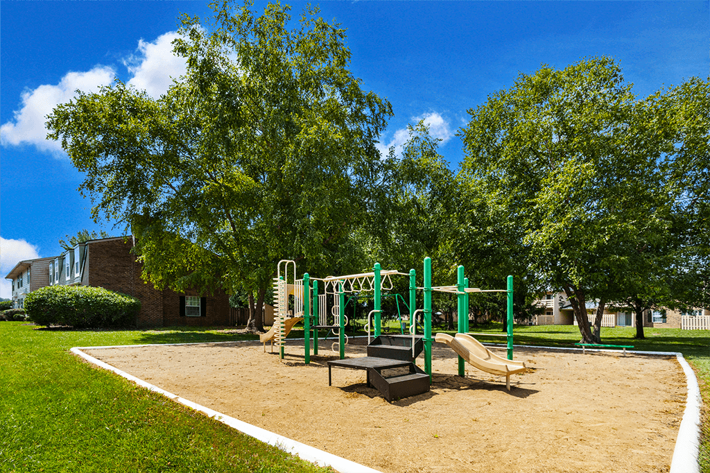 Playground at Briarwood Apartments, Columbus, IN, with swings, slides, and green space.