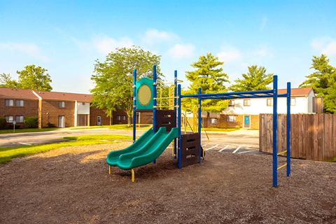 A playground with a green slide and a blue monkey bars.