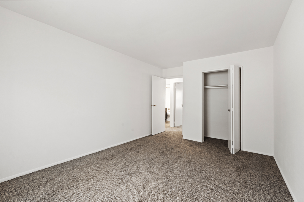 Spacious primary bedroom in a two-bedroom, one-bath Windsor Park apartment, with carpeted floors and a closet.