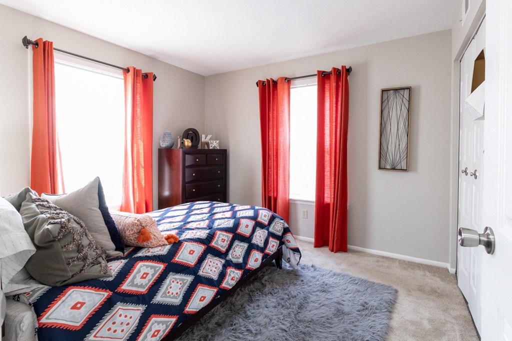 a bedroom with red curtains and a bed and a rug