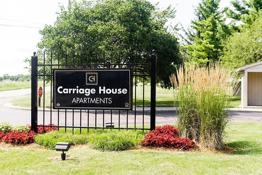 a black wrought iron gate with a sign for carriage house apartments