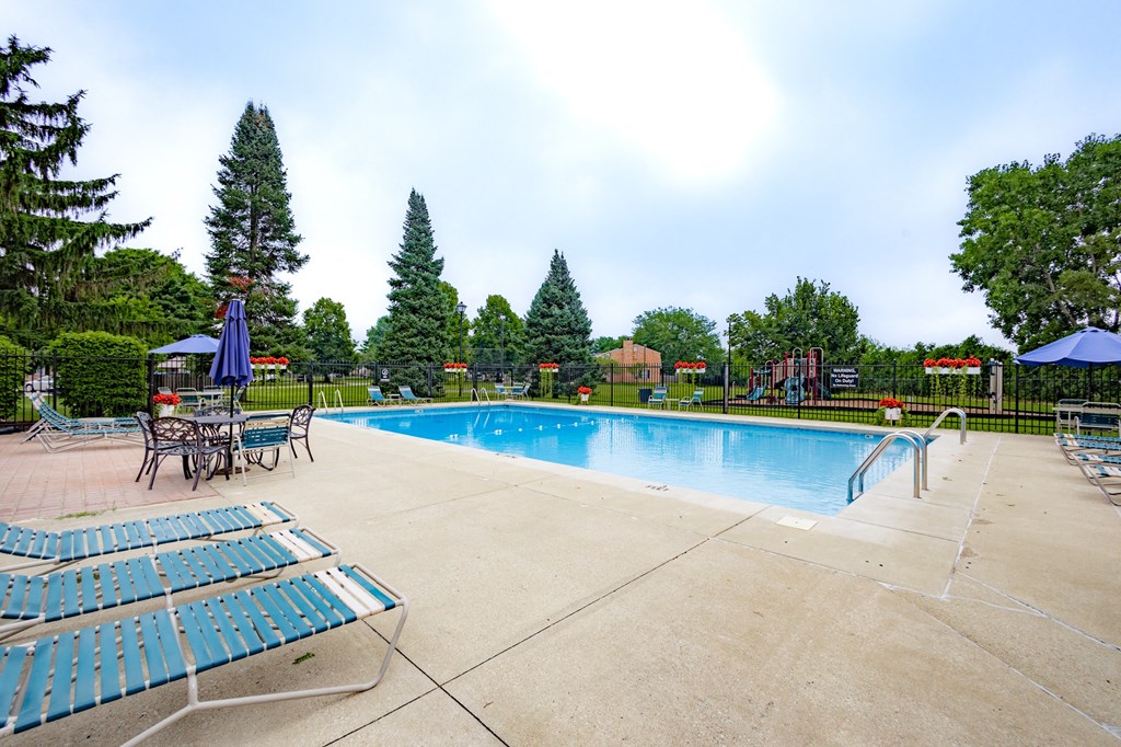 a swimming pool with chairs and umbrellas and trees