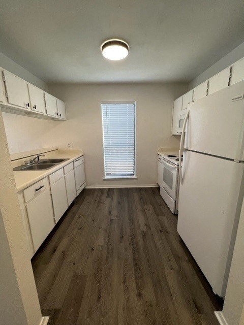 a kitchen with white appliances and a wood floor