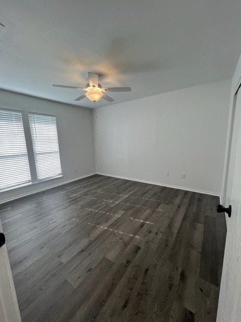 an empty living room with a ceiling fan and wood floors