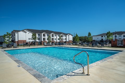 A swimming pool in front of a building with a metal ladder.