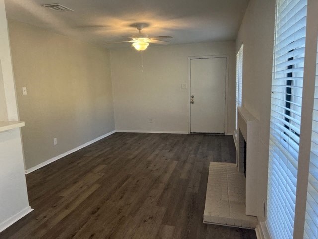 an empty living room with wood floors and a ceiling fan