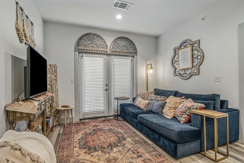 A living room with a dark blue couch and a rug with a pattern on it.