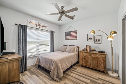 A bedroom with a bed, nightstand, and a ceiling fan.