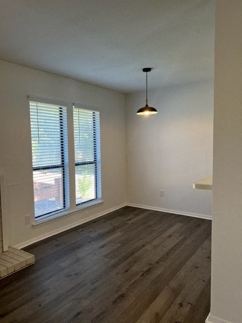 an empty living room with a lamp and two windows