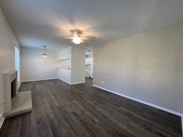 an empty living room with a fireplace and a ceiling fan