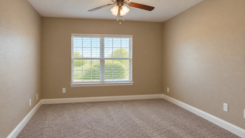 A room with a ceiling fan and a window with blinds.