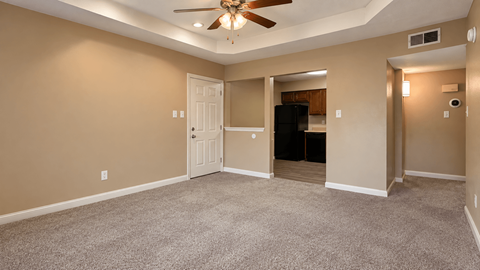 A room with a ceiling fan and carpeted floor.