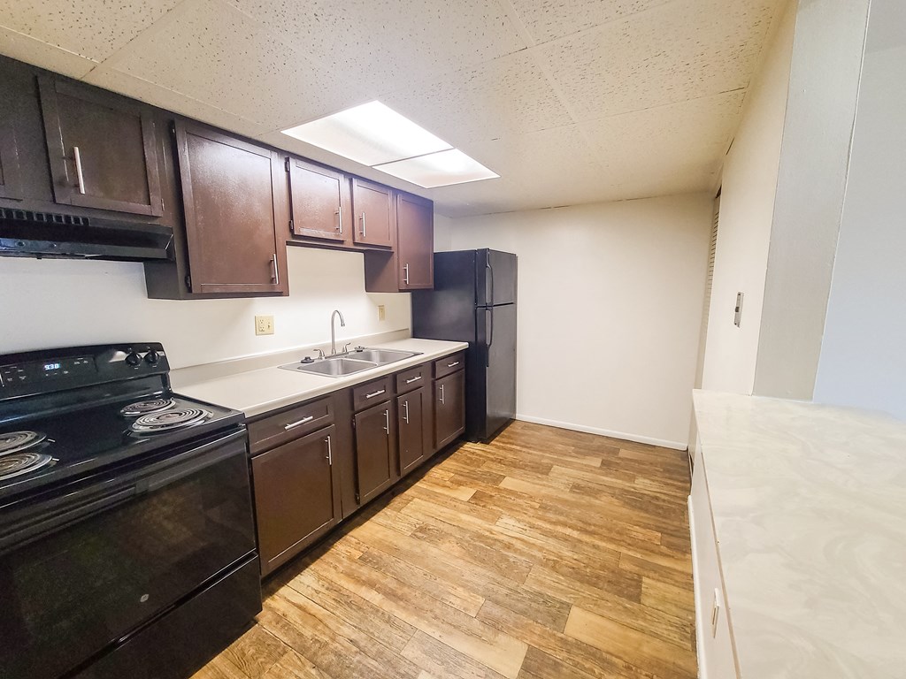 A kitchen with dark brown cabinets and a black stove top oven.